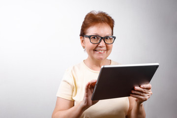 Fototapeta premium senior woman in glasses with a tablet on a white background in a light T-shirt. place for text, isolated