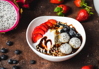 chia bowl with strawberries, blueberries, fruits and nuts on a brown background