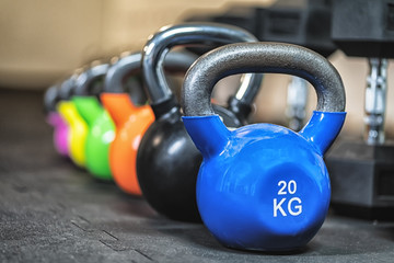 Naklejka na ściany i meble Row of colorful kettlebell weights in the gym