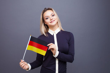 Immigration and the study of foreign languages, concept. A young smiling woman with a Germany flag in her hand.