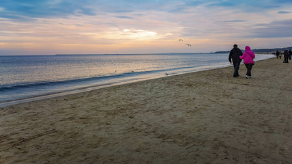 People walking on beach near water over Baltic Sea in Swinoujscie at november