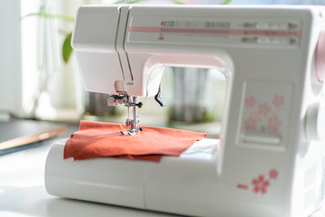Sewing machine on the white table in fron of the window