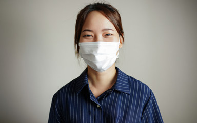 Asian, Thai woman wearing a medical face mask protection in prevention for coronavirus or COVID-19 on a white wall background in studio portrait  concept protects against the spread for coronavirus 