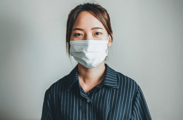 Asian, Thai woman wearing a medical face mask protection in prevention for coronavirus or COVID-19 on a white wall background in studio portrait  concept protects against the spread for coronavirus 