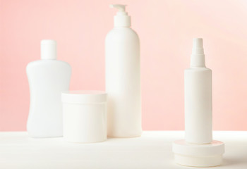 White cosmetic bottles on pink background. Top view