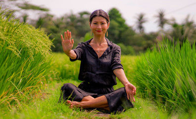 Naklejka na ściany i meble outdoors yoga and meditation at rice field - attractive and happy middle aged Asian Korean woman enjoying yoga and relaxation in connection with the nature