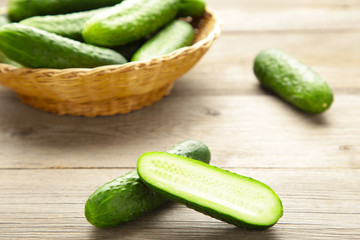Fresh cucumbers in basket on grey background.