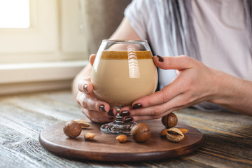 Woman is holding a transparent glass with delicious and refreshing whipped coffee. A trendy spectacular drink that can made at home