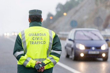 Guardia Civil officer next to a speed control monitors traffic on a highway on a rainy day
