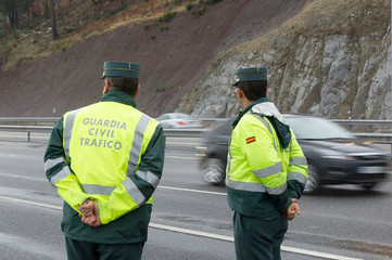 Guardia Civil officer watch traffic on a highway on a rainy day