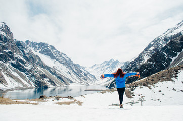 A young adult woman posing with open arms while appreciating the view of the Andes Mountains in...