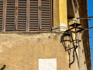 Photograph of a corner of an old building with an old rusty lamppost and a lot of electric wires