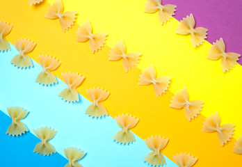 Close up pattern of noodles farfalle also known as bow-tie or butterfly pasta placed on colorful background.