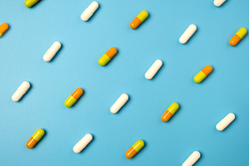Close up of many different pills arranged in pattern on blue background.