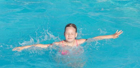 Fototapeta na wymiar the girl can't swim and is afraid of drowning. Child having fun in swimming pool. Kid playing outdoors. Summer vacation and healthy lifestyle concept