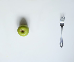 green apple i fork on a white table