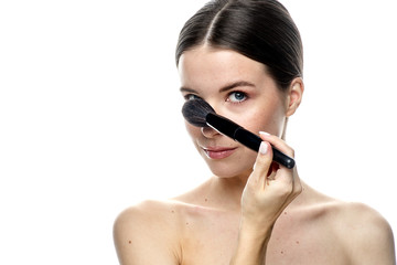 close-up portrait of a girl without makeup with clean skin with a makeup brush in hand, isolated on a white background