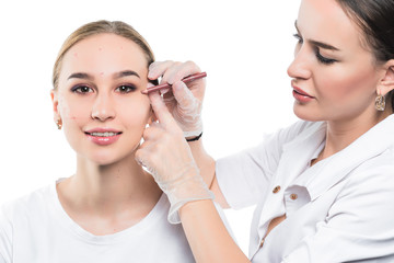 A cosmetologist examines the patient face and plans to perform a series of cosmetic procedures