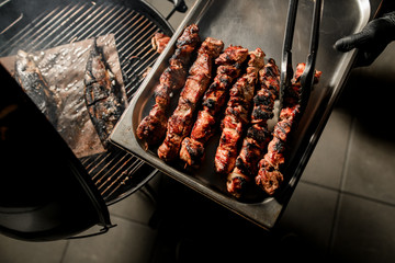 Top view how male chef removes fried pieces of beef meat from grill to metal tray
