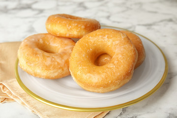 Delicious glazed donuts on marble table, closeup