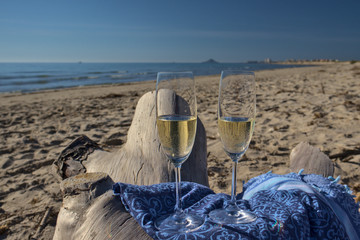 copas de champán, sobre un tronco de una playa virgen del mediterráneo. 