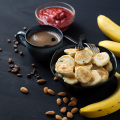 mini pancakes for Breakfast with coffee, strawberry jam, bananas and almonds