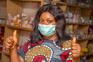 african woman who owns a small business standing in her store giving thumbs up