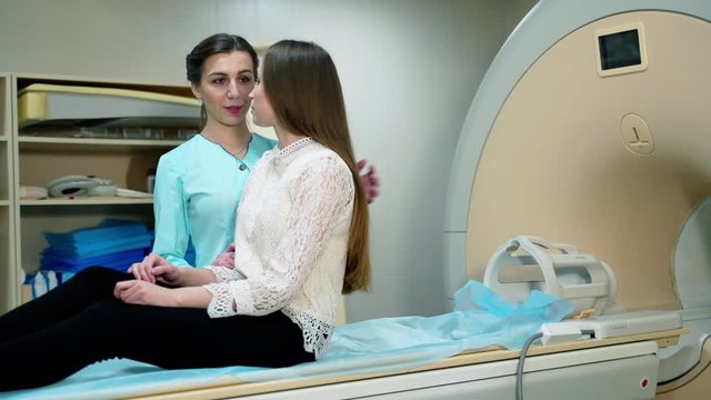 Medical examination concept. Young woman before a tomographic scan in clinic.Nurse preparing patient for magnetic resonance image.