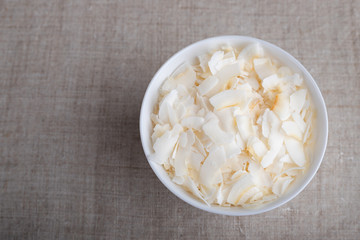 Coconut chips in a bowl on the table. Top view.