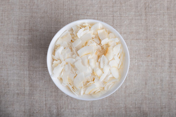 Coconut chips in a bowl on the table.Top view.
