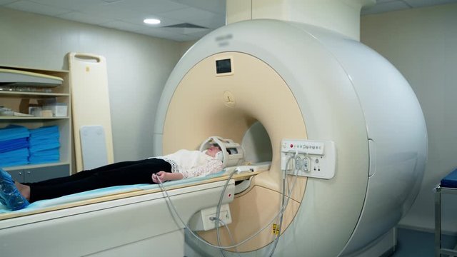 Patient in a hospital MRI scanner. Woman lays in Magnetic resonance image device. Woman patient is doing tomographic scanning in clinic.