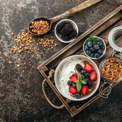 Healthy breakfast with granola, yogurt, fruits, berries on dark metal background. Summer homemade breakfast.