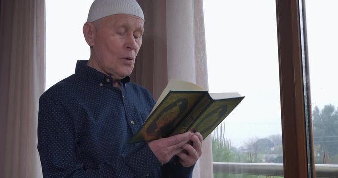 An old muslim man reading Koran at home