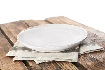 Empty plate and napkin on wooden table against white background