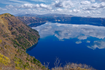 曇り空の下の湖の風景。湖面に映る空。摩周湖、北海道、日本。