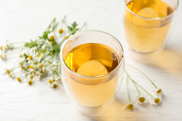 Delicious chamomile tea in glass on white table