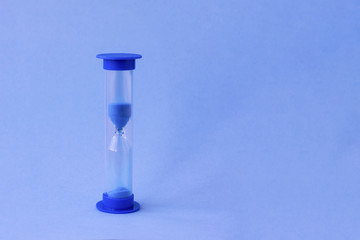 Hourglass with falling sand inside of them as a symbol of running time, lifetime and leak of time. Sand watches with a big amount of blue sand as metaphor of lot of time.