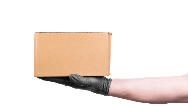 Male hand in a disposable black glove holds a cardboard box - safe delivery of goods, isolate on a white background, copy space