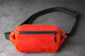 Red waist bag made of leather, banana on a gray background.