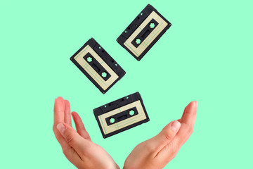 vintage audio tapes flying into female hands on a green background