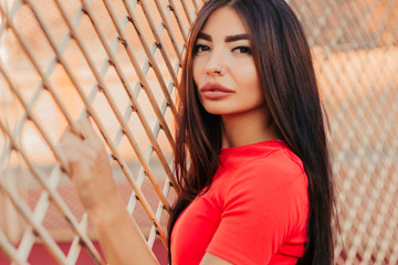 Beautiful fitness woman in sportswear posing near grid.