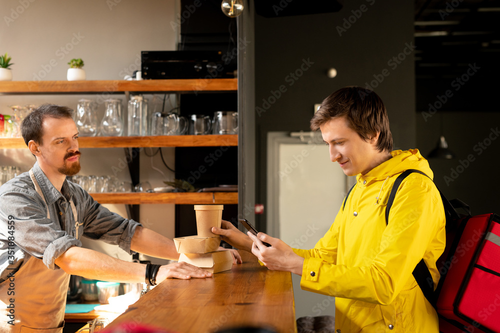 Poster young courier with backpack looking at client address in smartphone