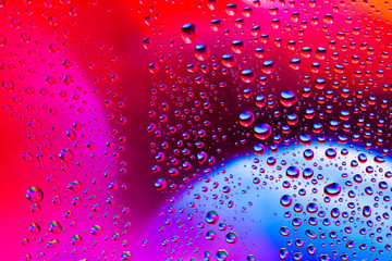 Abstract with water drops on glass against a background of light from a prism and pink shades