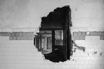 A hole in the wall of a large tiled building. Black and white image. Background