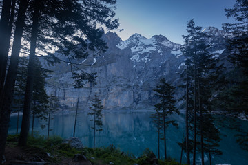 Oeschinensee im Berner Oberland bei Sonnenaufgang, wolkenloser Himmel, blaues Wasser 