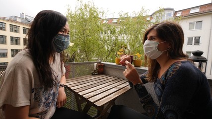 Girlfriends chating at home wearing masks