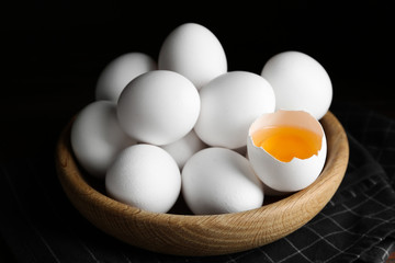 Many fresh raw chicken eggs in bowl on table
