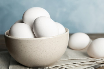 Many fresh raw chicken eggs in bowl on table, closeup