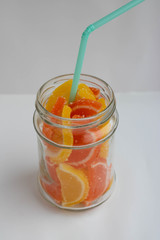 Dessert marmalade in the form of slices of lemon and orange in a jar. Sweet yellow and orange jelly candies.
