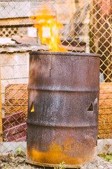 A hot searing fire in an old rusty iron barrel of garbage
